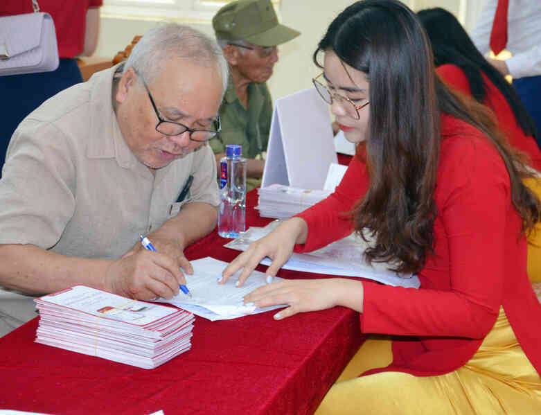 Cán bộ Ngân hàng Nông nghiệp và Phát triển nông thôn Chi nhánh Bãi Cháy hướng dẫn cán bộ hưu trí phường Việt Hưng (TP Hạ Long) ghi thay đổi thông tin nhận lương hưu qua tài khoản thẻ ATM. Ảnh: Dương Trường